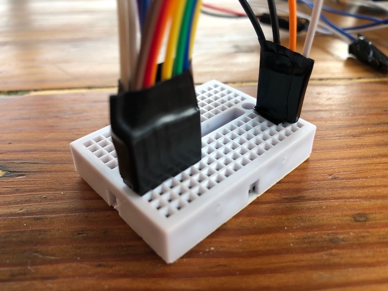 Wires with tape around them on a mini breadboard